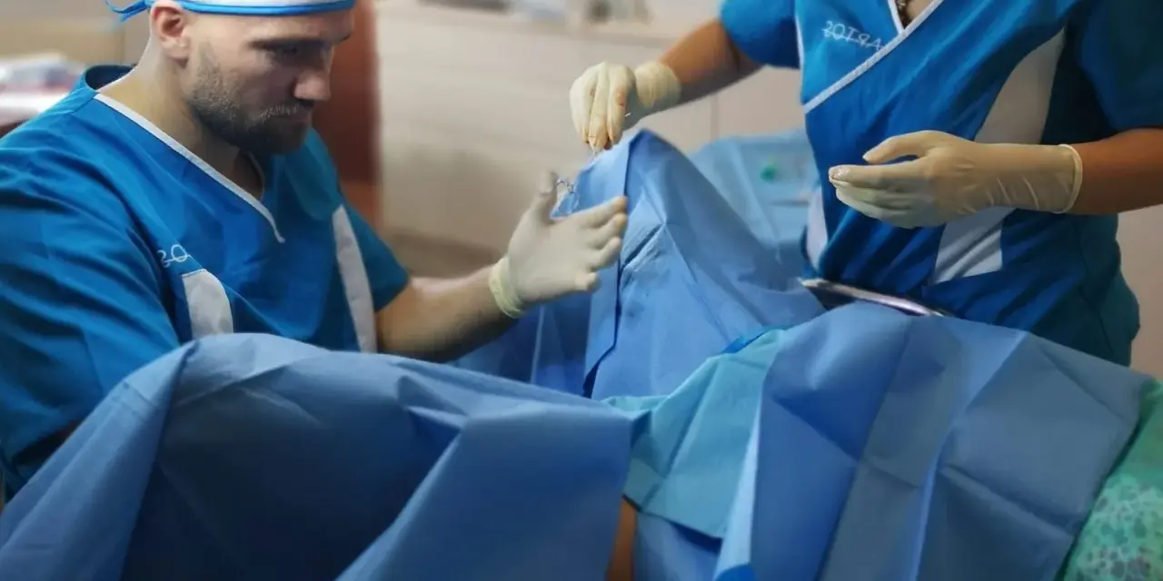 Chirurg i asystentka w rękawiczkach przygotowują się do zabiegu. Zdjęcia nieudana labioplastyka mogą pokazywać takie momenty.