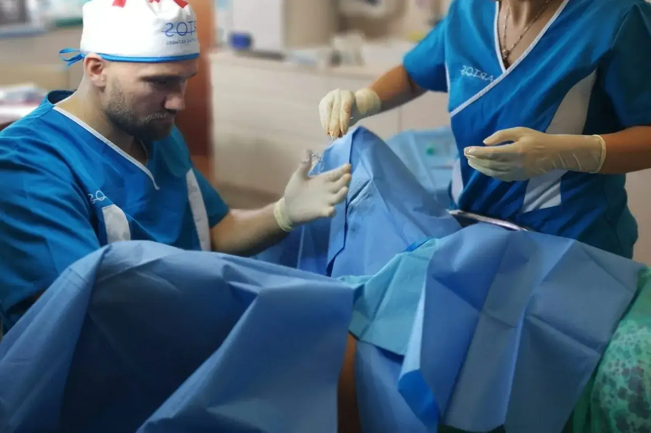Chirurg i asystentka w rękawiczkach przygotowują się do zabiegu. Zdjęcia nieudana labioplastyka mogą pokazywać takie sceny.